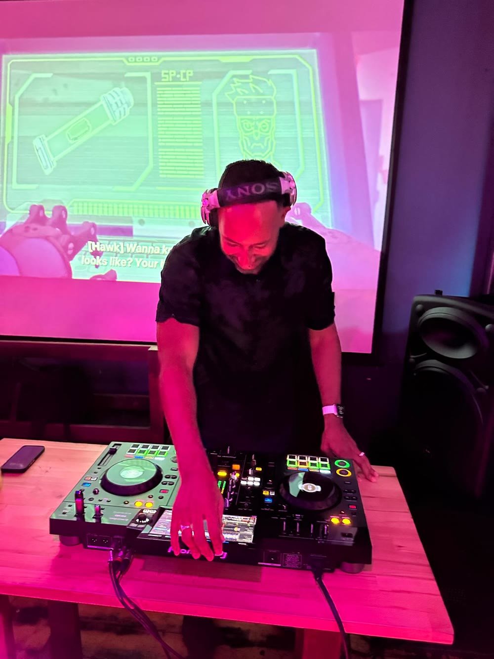 Matt Cox performing a DJ set under pink club lighting